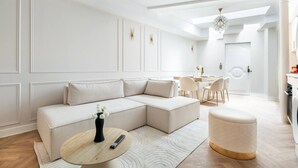 Un saló modern amb un sofà modular, una taula de centre rodona i una zona de menjador amb taula i cadires blanques.