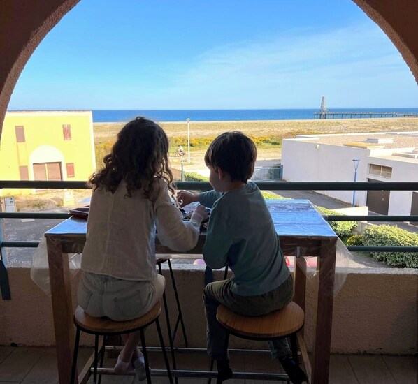 Two people seated at a table with a view of the sea and buildings in the background. - Studio port Leucate, first line beach (Leucate)