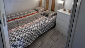 A small, well-lit bedroom with a single bed, a nightstand, and a window with curtains. - Studio port Leucate, first line beach (Leucate)