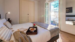 Quarto com cama, mesa de cabeceira, abajur, janela com vista e porta.