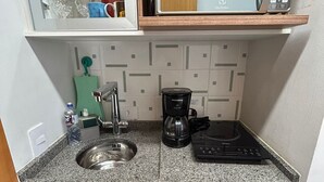 A compact kitchen with a microwave, coffee maker, sink, and a compact refrigerator. - Get a Flat - 604  Ibirapuera (São Paulo)