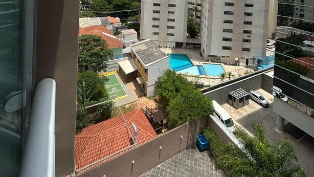 A high-rise building with a swimming pool and a view of the surrounding cityscape. - Get a Flat - 604  Ibirapuera (São Paulo)