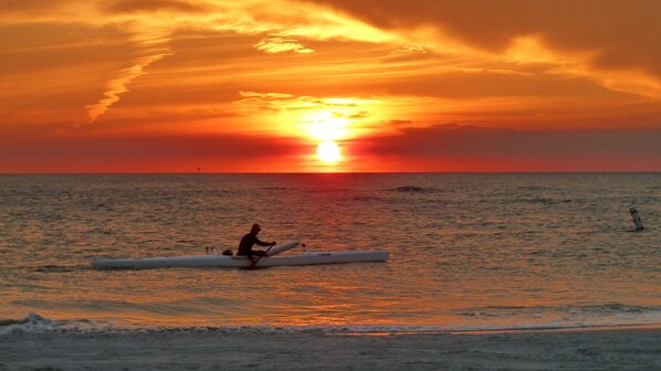 Un coucher de soleil sur lâocĂ©an, avec une personne Ă bord dâun kayak.