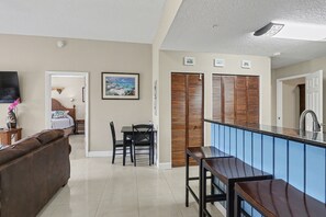 A modern kitchen with a blue backsplash, wooden cabinets, and a dining area with a table and chairs.
