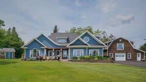 A two-story house with a front porch, a garage, and a well-maintained lawn. - Harbourview Retreat - Waterview Luxury Home Steps from the Inn at Bay Fortune (Rock Barra)