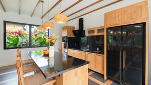 Una cocina moderna con armarios de madera, un refrigerador negro y una isla central con un florero.