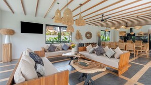Una sala moderna con sofá, sillas, una mesa de centro y una zona de comedor con muebles de madera.