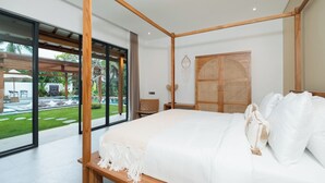 Un dormitorio moderno con una cama grande, vigas de techo de madera, un armario de ratán y vistas a una piscina y jardín.