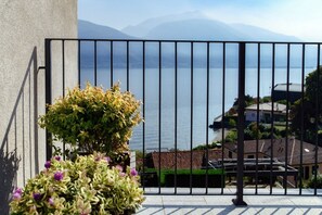 A balcony with a metal railing, a potted plant, and a view of a lake and mountains. - Villa Jolie - My Home in Como (Calozzo)