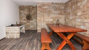 A rustic stone wall with a wooden bench and a picnic table. - Holiday home Rozara by Villas Guide (Primošten)