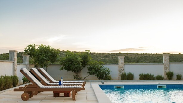 A poolside area with lounge chairs and a pool. - Holiday home Rozara by Villas Guide (Primošten)
