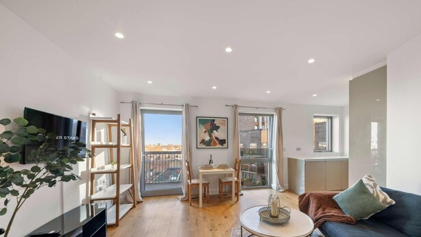 A modern living room with a sofa, a dining table, and a TV. - Bywell Apartment, Canning Town, London (Greater London)