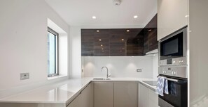 Een moderne keuken met een inbouwoven, een magnetron en een spoelbak.