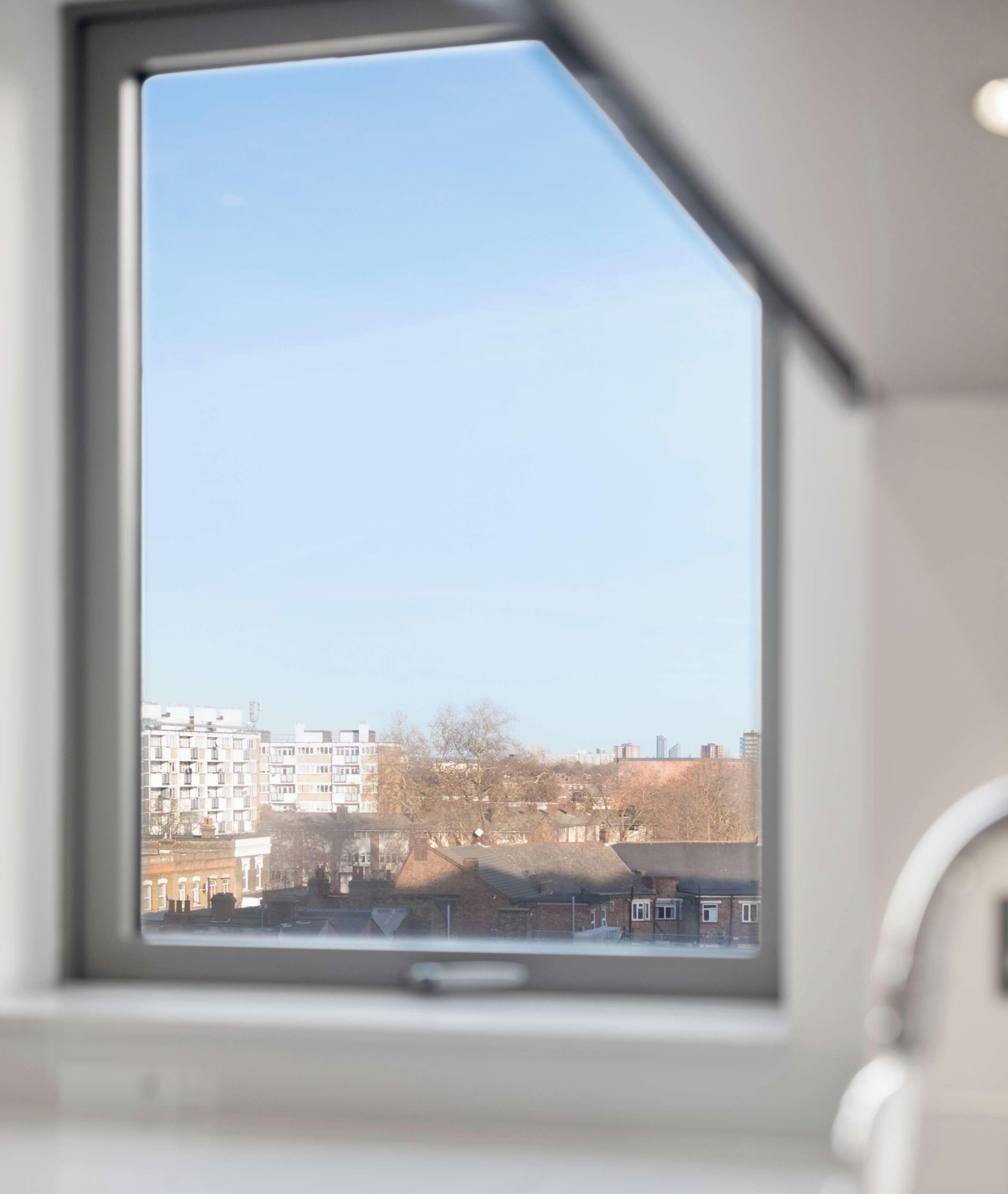 Ein Fenster mit Blick auf eine Stadtlandschaft, einschließlich Gebäude und Bäume.