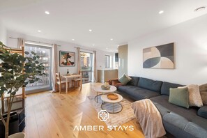 Ein modernes Wohnzimmer mit einer Couch, einem Couchtisch und einem Essbereich mit Stühlen und einem Tisch.