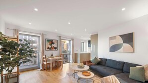 A modern living room with a sofa, coffee table, and dining area. - Bywell Apartment, Canning Town, London (Greater London)