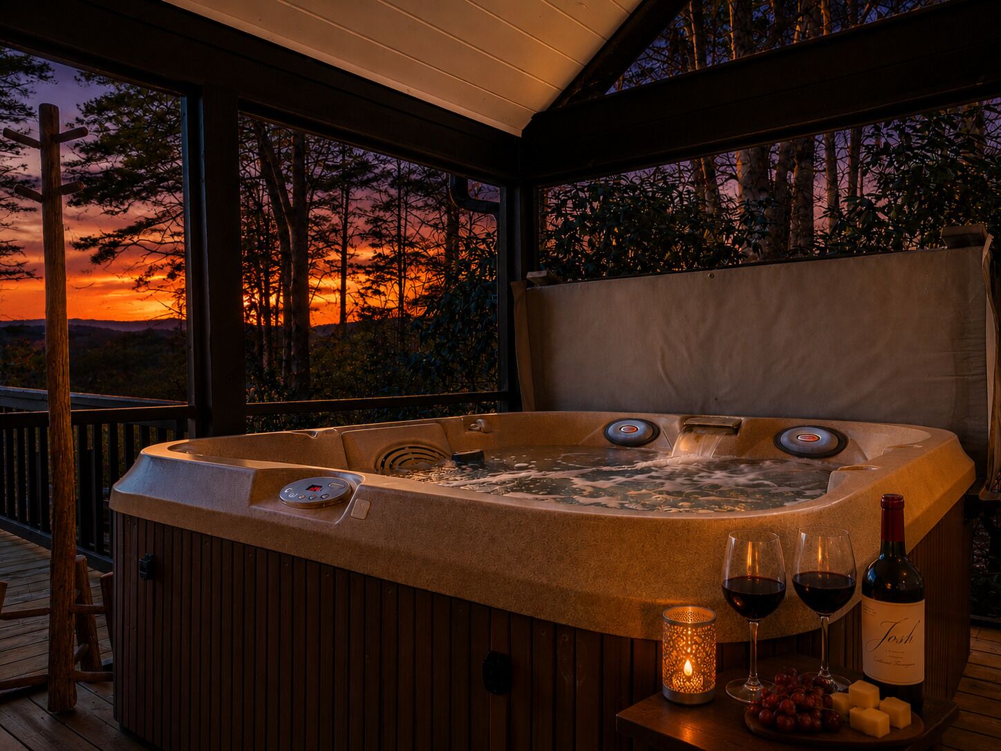 A hot tub with a control panel, two glasses of red wine, a bottle of wine, and a candle on a wooden table.
