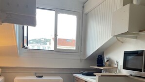 Eine kleine Küche mit weißer Arbeitsplatte, einer Mikrowelle und einer Kaffeemaschine.