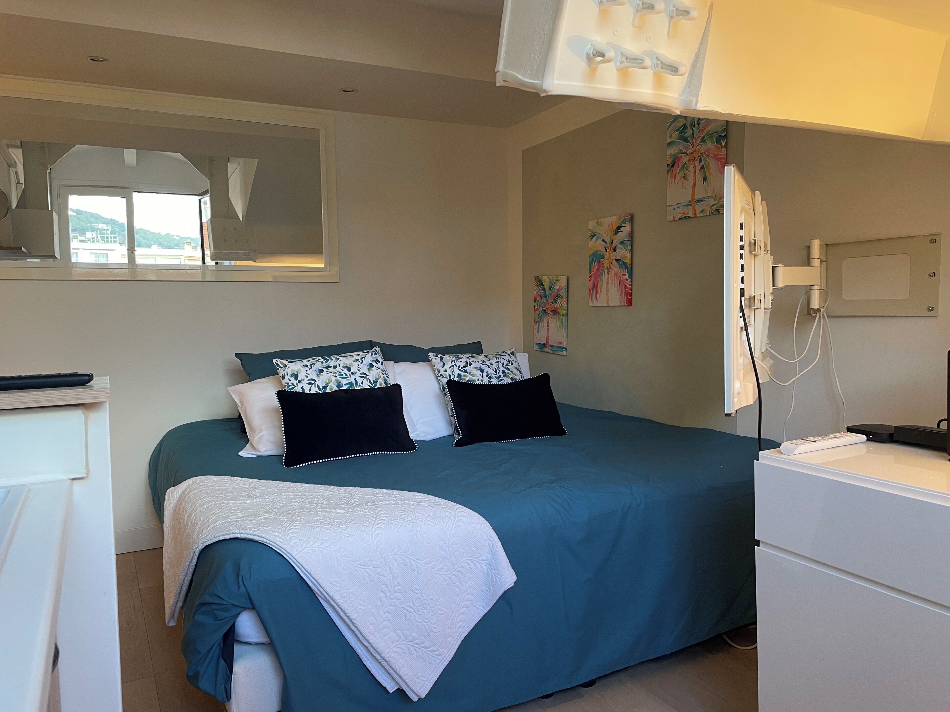 A bedroom with a bed, a desk, and a window.