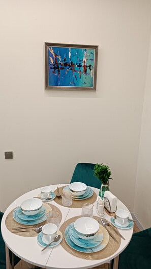 A dining table set with blue and white plates, bowls, and cutlery, with a framed abstract painting above. - Cozy 1-bedroom apartment in a fantastic Almaty neighborhood (Almaty)