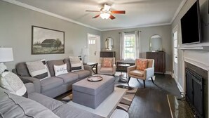 A living room with a gray sofa set, a coffee table, a fireplace, and a television mounted on the wall. - The Franklin Suite- Near Jennings Sports Complex (Lewis Center)