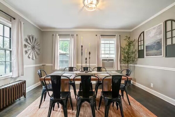 Una sala da pranzo con un tavolo grande, sedie nere e un elemento decorativo a parete.