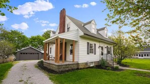 A single-story house with a front porch, a chimney, and a garage in the background. - The Franklin Suite- Near Jennings Sports Complex (Lewis Center)