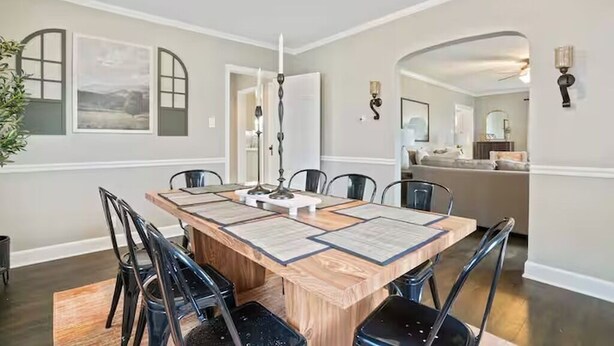 A dining area with a wooden table, black chairs, and a chandelier. There are framed pictures on the wall and a plant on the left. - The Franklin Suite- Near Jennings Sports Complex (Lewis Center)