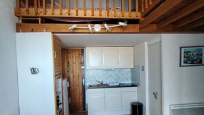 Ein kompakter Wohnraum mit Küche, Essbereich und einer Treppe zu einer oberen Ebene.
