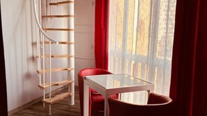 A room with a glass table, red chair, and a spiral staircase. - Residence with swimming pool and sea view - Haven of peace in the heart of the city (Le Barcarès)