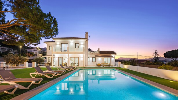 Ein zweistöckiges Haus mit Swimmingpool und Liegestühlen.