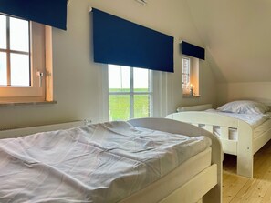 A bedroom with two beds, a window, and a radiator. - Cozy Friesenhuus with field edge location on the old dike (Carolinensiel)