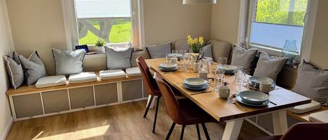 A dining area with a wooden table set for four, surrounded by cushioned seating.