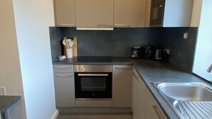 A compact kitchen with a built-in oven, a sink, and a coffee maker. - Border Lodge - Comfort just a stone's throw from the border (Évrange)
