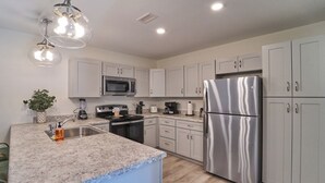 Una cocina moderna con armarios blancos, electrodomésticos de acero inoxidable y encimera de granito.