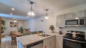 Una cocina moderna con encimeras de granito, electrodomésticos de acero inoxidable e iluminación colgante.