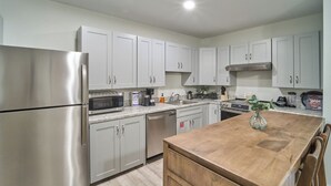 A modern kitchen with stainless steel appliances, white cabinets, and a wooden island. - Ruby 102: 1BD | Great LOCATION + Shared Amenities! (Pigeon Forge)