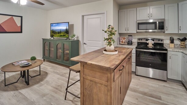 Una cucina moderna con isola in legno, elettrodomestici in acciaio inossidabile e un armadietto verde.