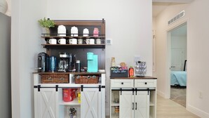 Una kitchenette con estación de café, armarios de almacenamiento y una pequeña zona de comedor.