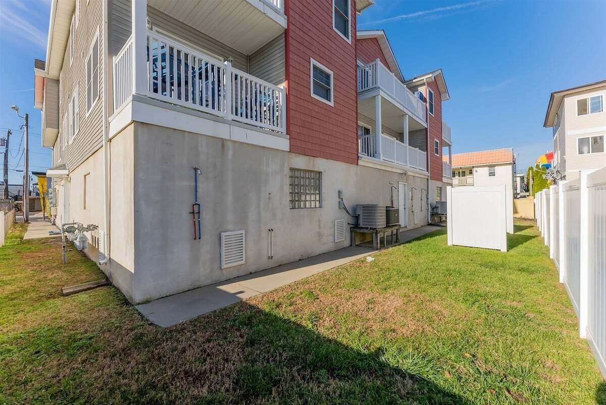 A multi-story residential building with balconies, a concrete facade, and a small lawn area.