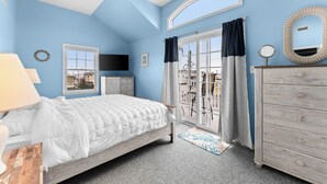 Een slaapkamer met een bed, een dressoir, een televisie, een raam en uitzicht op buiten.