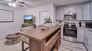 Una cocina moderna con armarios blancos, electrodomésticos de acero inoxidable y una isla de madera.