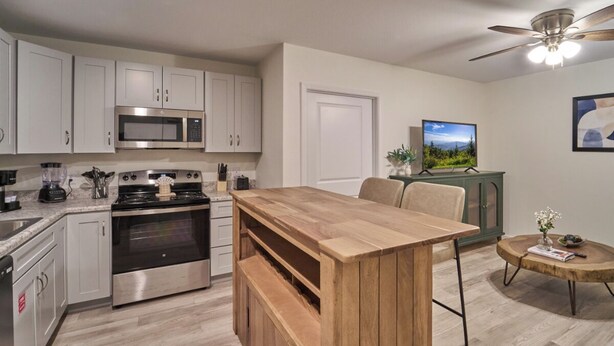 Una cocina moderna con armarios blancos, electrodomésticos de acero inoxidable y una isla de madera.
