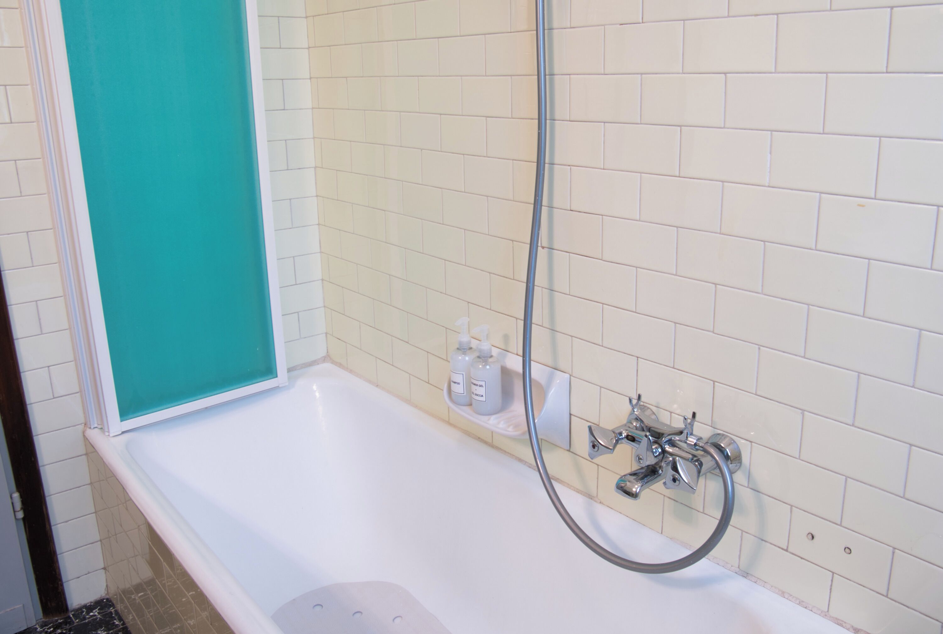 Une salle de bain avec une baignoire blanche, une pomme de douche et une étagère contenant des articles de toilette.