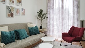 A living room with a sofa, red chair, small round table, and wall art. - Barzio - Garden - Primula (Barzio)