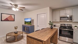 A modern kitchen with a wooden island, stainless steel appliances, and a ceiling fan. - Ruby 108: 1BD | Great Location+ Shared Amenities! (Pigeon Forge)