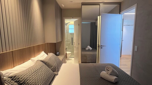 Ett modernt hotellrum med två sängar, en stor spegel och en rymlig klädkammare.