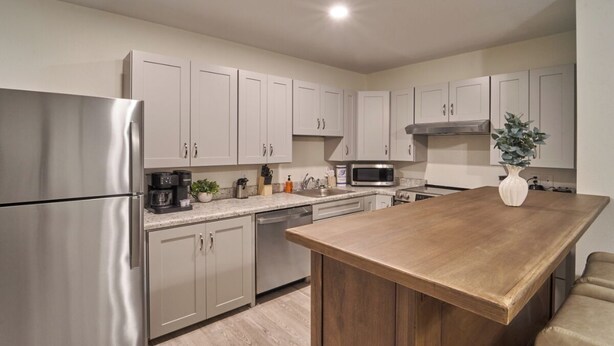 A modern kitchen with stainless steel appliances, light-colored cabinets, and a wooden island. - Ruby 109: 1BD | Great Location + Shared Amenities! (Pigeon Forge)