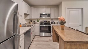 A modern kitchen with stainless steel appliances, white cabinets, and a wooden island. - Ruby 113: 1BD | Great Location + Shared Amenities! (Pigeon Forge)