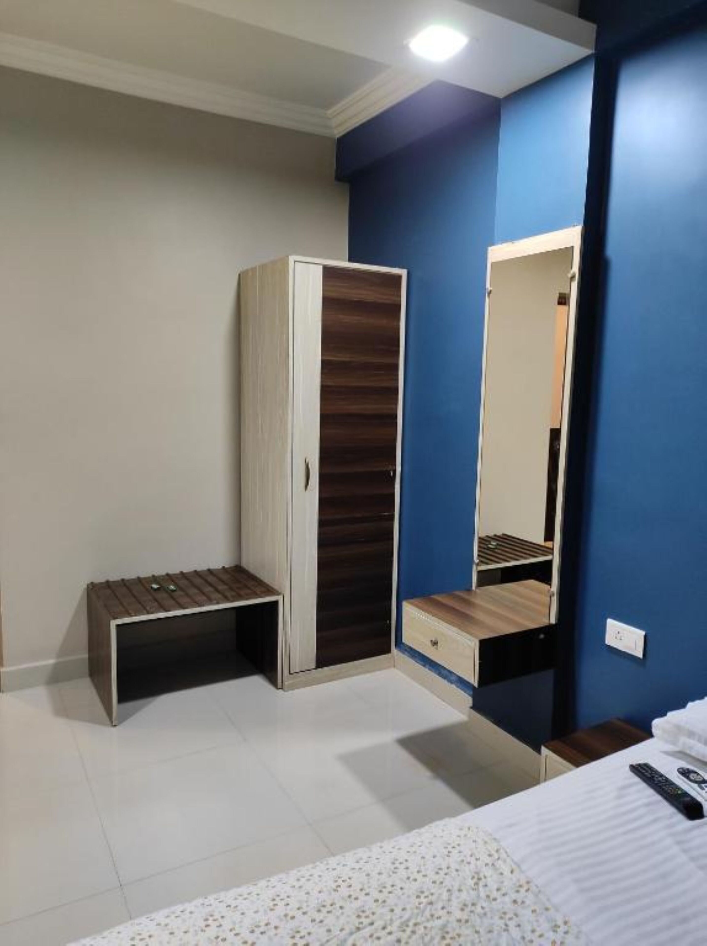 A bedroom with a wardrobe, a bedside table, a mirror, and a bed.
